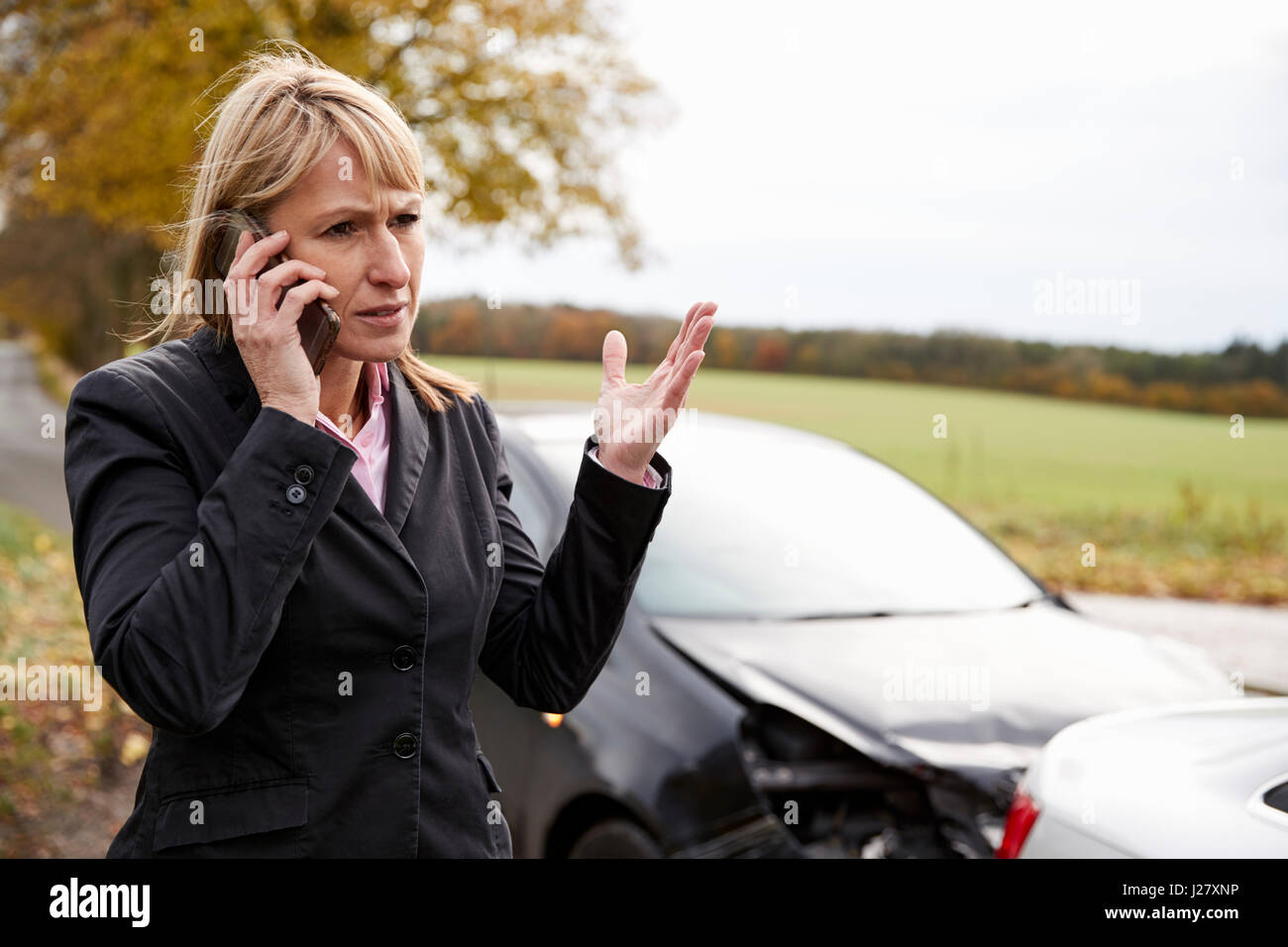 Donna che chiama alla relazione incidente di auto sulla strada di campagna Foto Stock