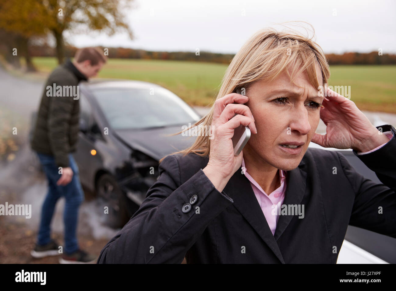 Donna che chiama alla relazione incidente di auto sulla strada di campagna Foto Stock