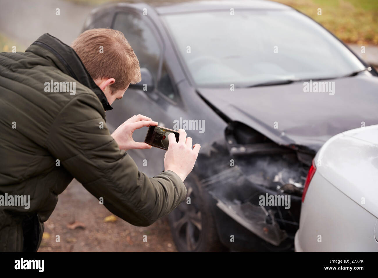L'uomo prendendo foto di incidente stradale sul telefono cellulare Foto Stock