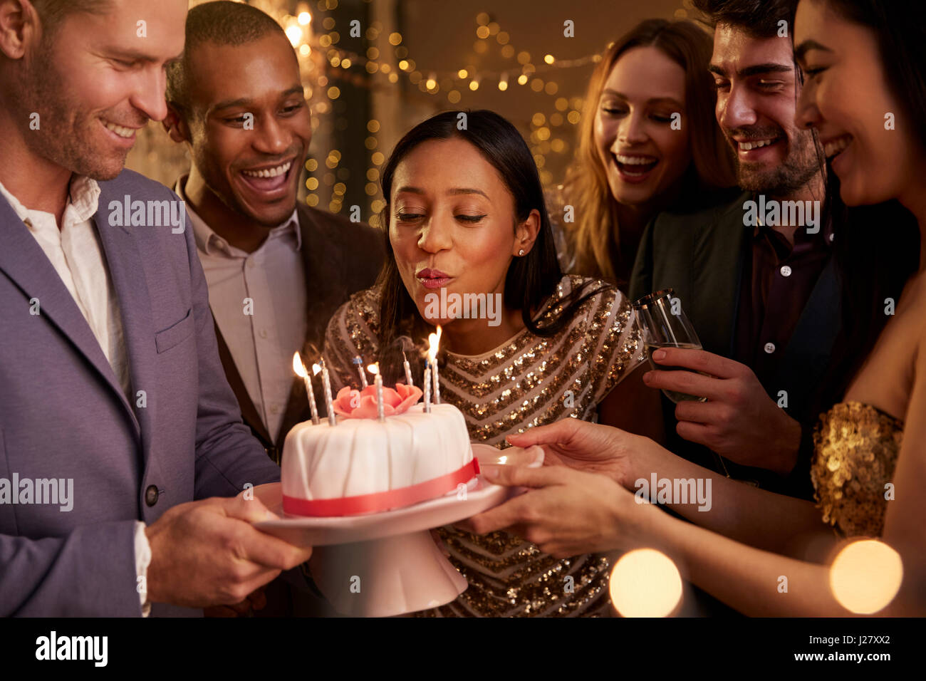 Donna soffiando le candeline sulla torta di compleanno Foto Stock