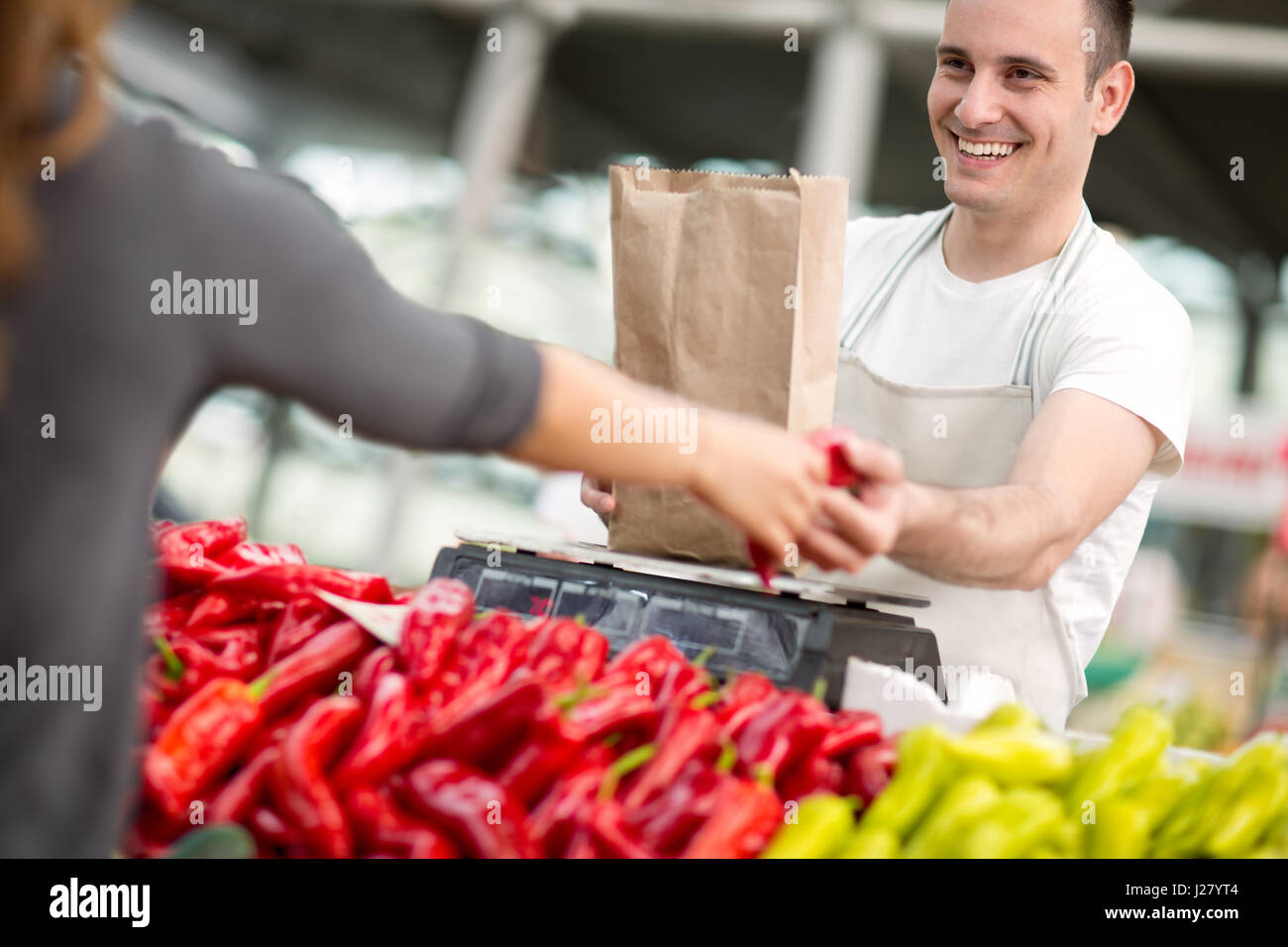 Sorridente venditore di pepe di misura al mercato Foto Stock