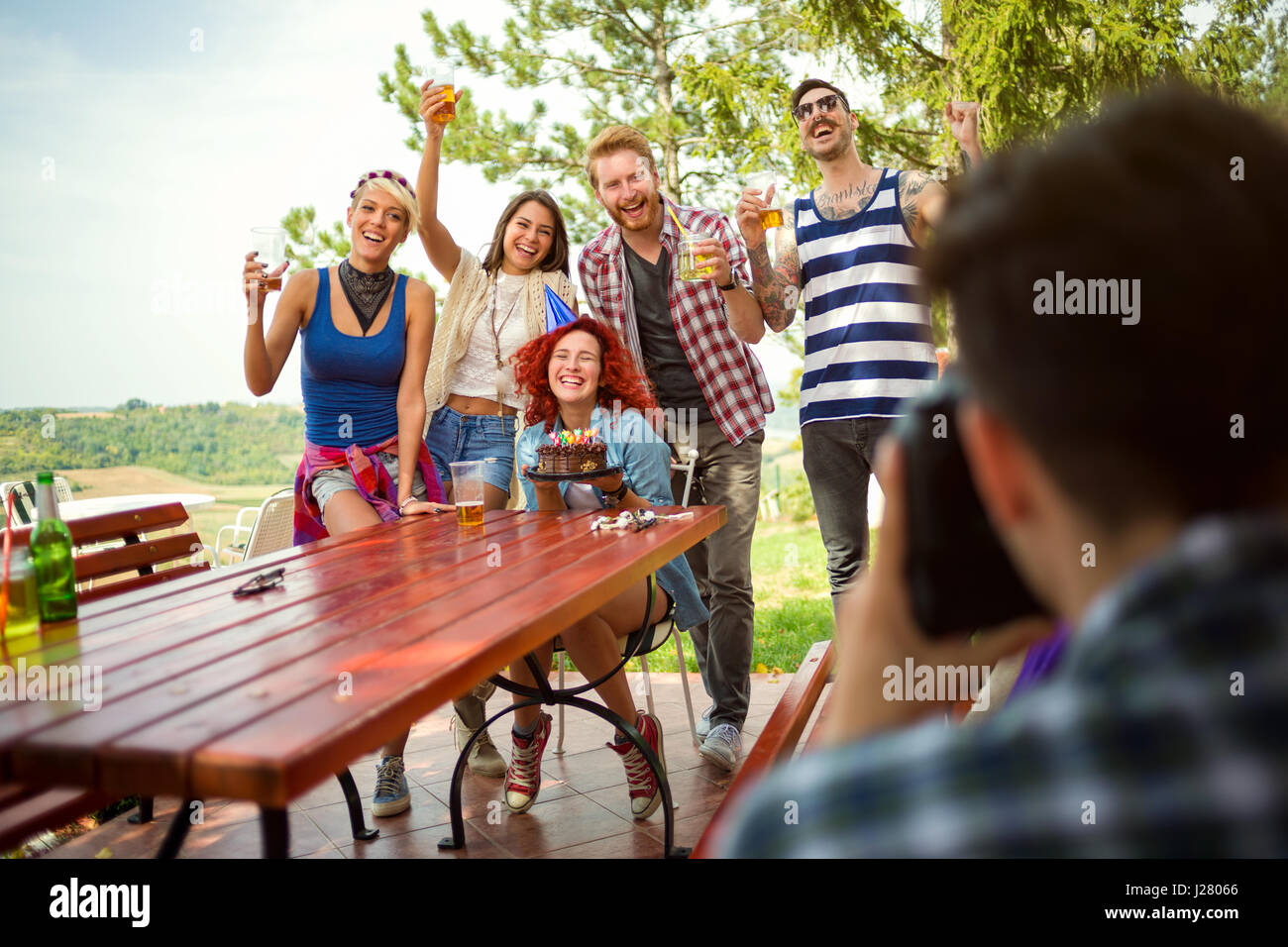 Foto di gruppo con la ragazza di compleanno e amici con gli occhiali di sollevamento cheers in natura Foto Stock