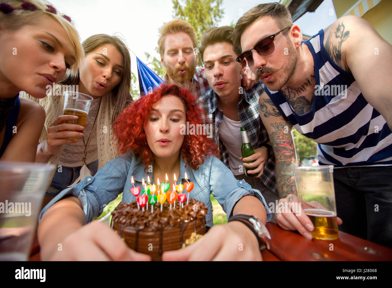 Compleanno ragazza soffia candele sul cioccolato torta di compleanno con gli amici Foto Stock