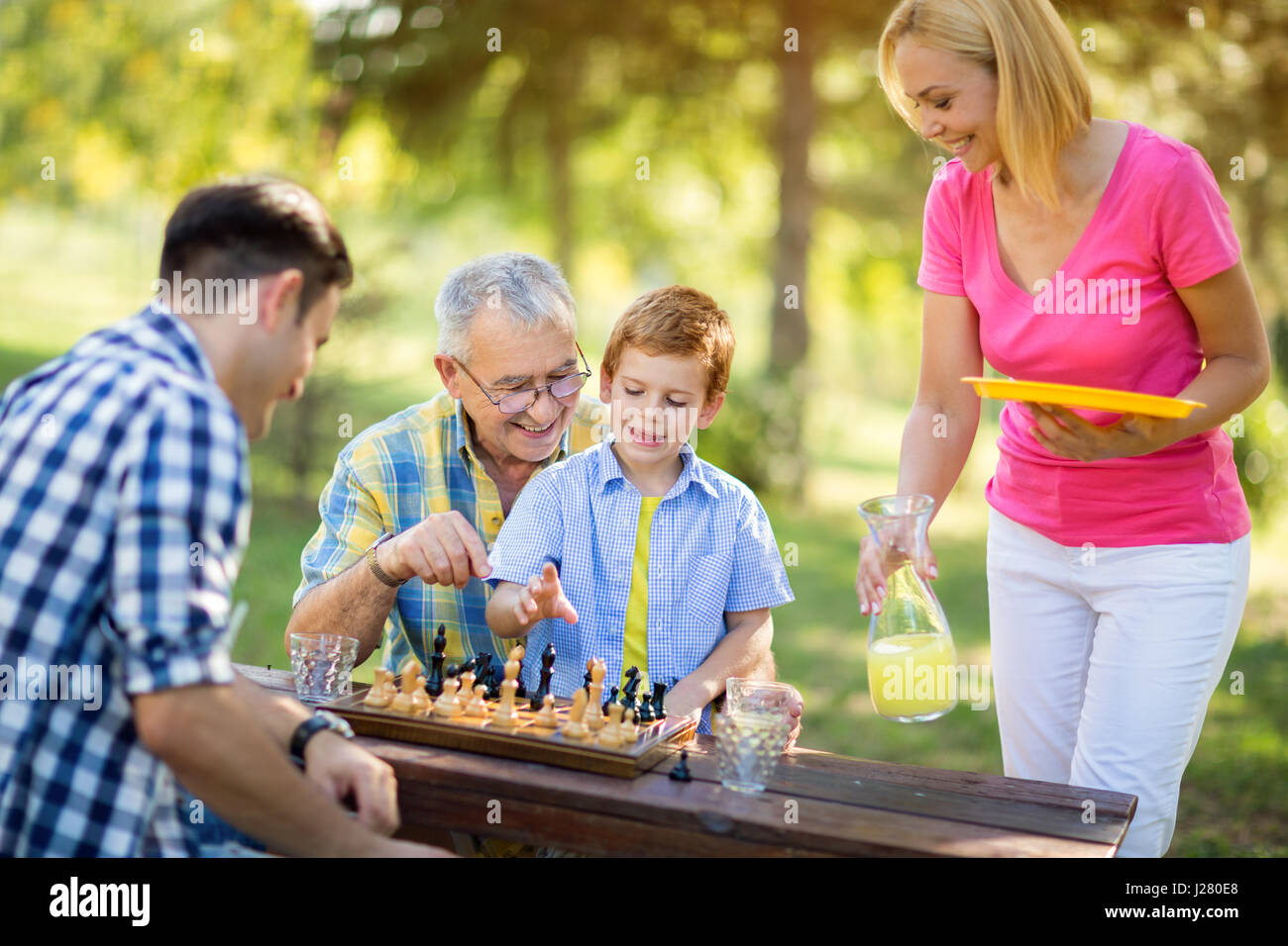 Famiglia sorridente rilassante giocare a scacchi nel parco Foto Stock