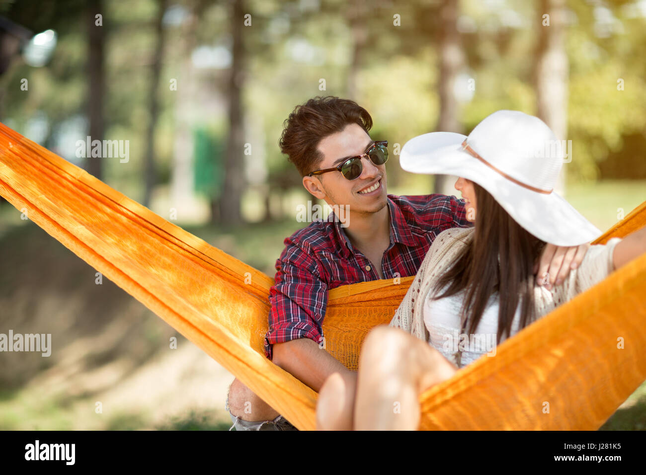 Giovane ragazzo abbracciando bella ragazza in arancione amaca in foresta Foto Stock