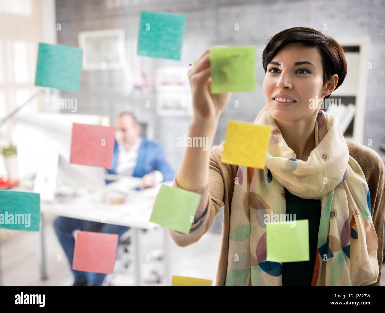 Giovani designer femmina in design studio fare schizzo su un memo adesivi Foto Stock