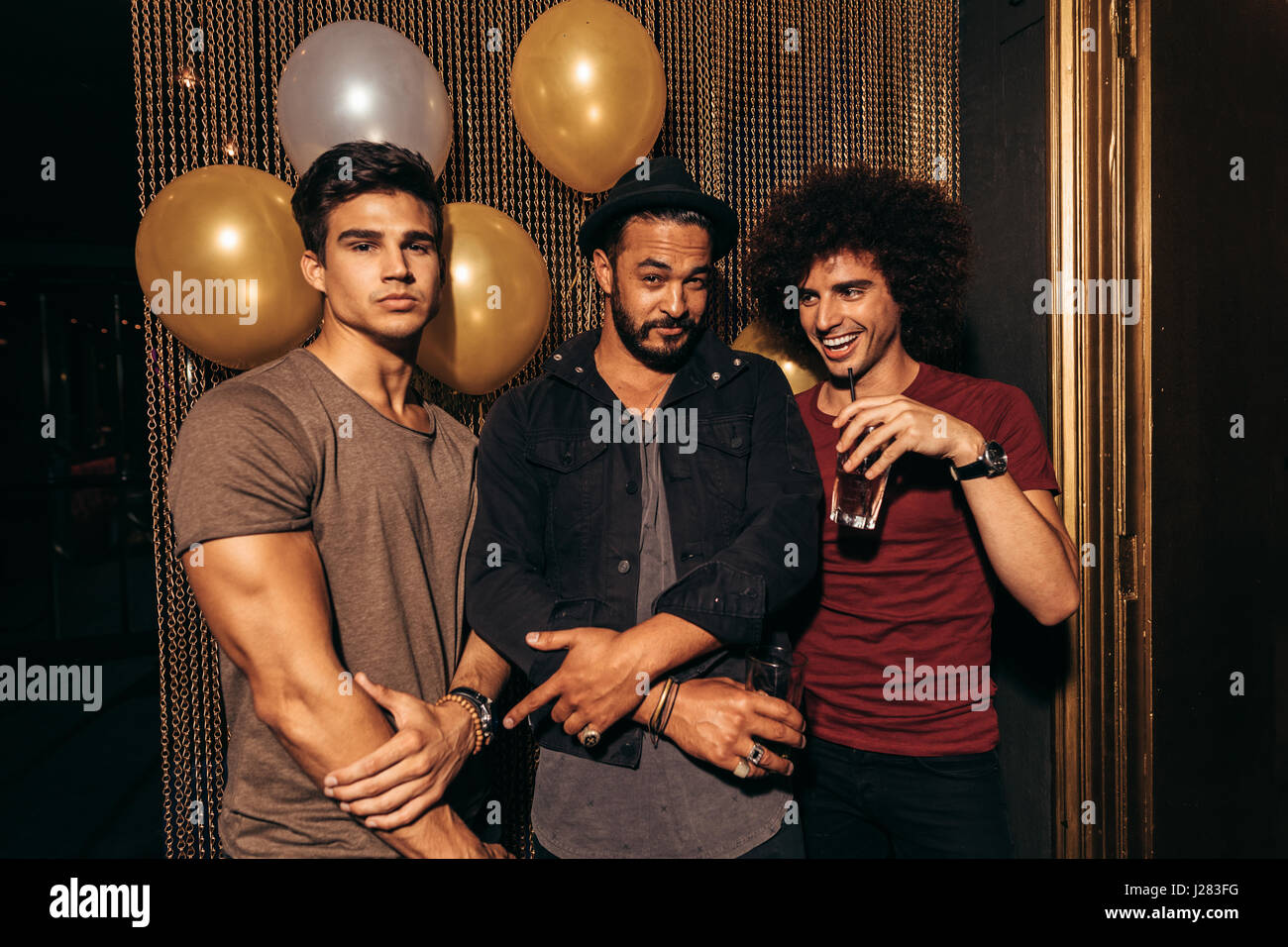 Ritratto di tre giovani uomini che partying al night club. Gruppo di uomini aventi buona volte al pub. Foto Stock