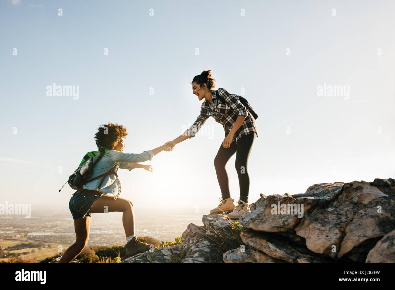 Giovane donna aiutando un amico a salire la roccia. Due giovani femmine escursioni nella natura. Foto Stock