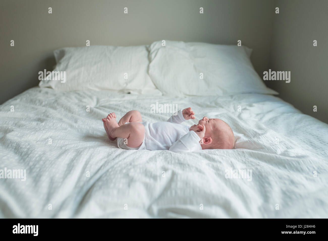 Vista laterale del neonato ragazzo mentre giaceva a letto a casa Foto Stock