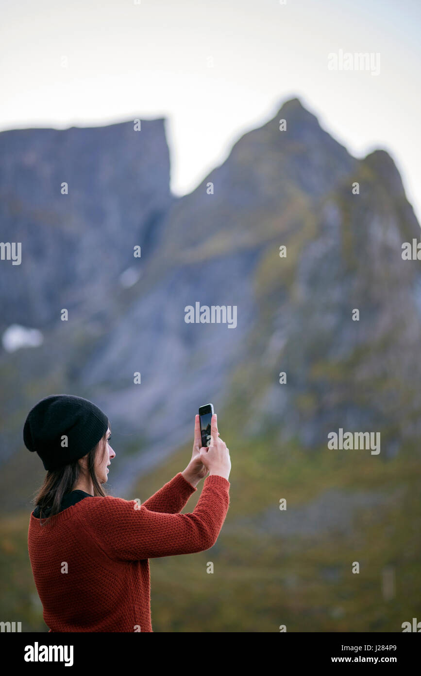 Vista laterale della donna a fotografare le montagne attraverso il telefono cellulare Foto Stock
