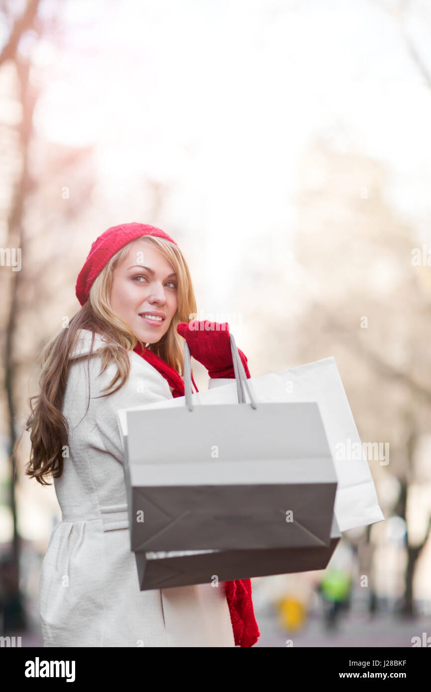 Una shopping donna caucasica il trasporto delle borse della spesa in un outdoor shopping mall Foto Stock