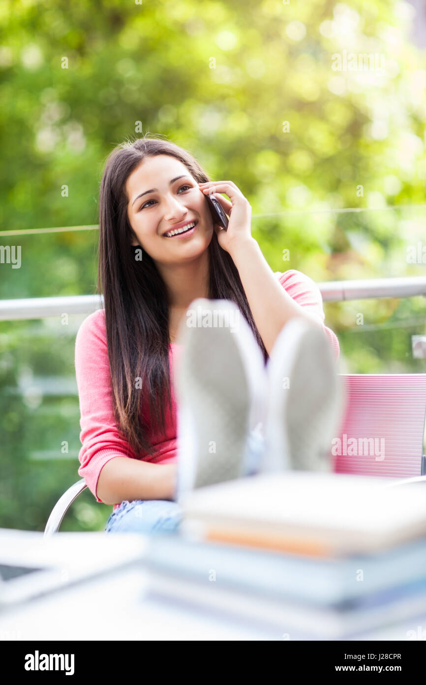 Un bellissimo ispanico studente di college a parlare al telefono del campus Foto Stock