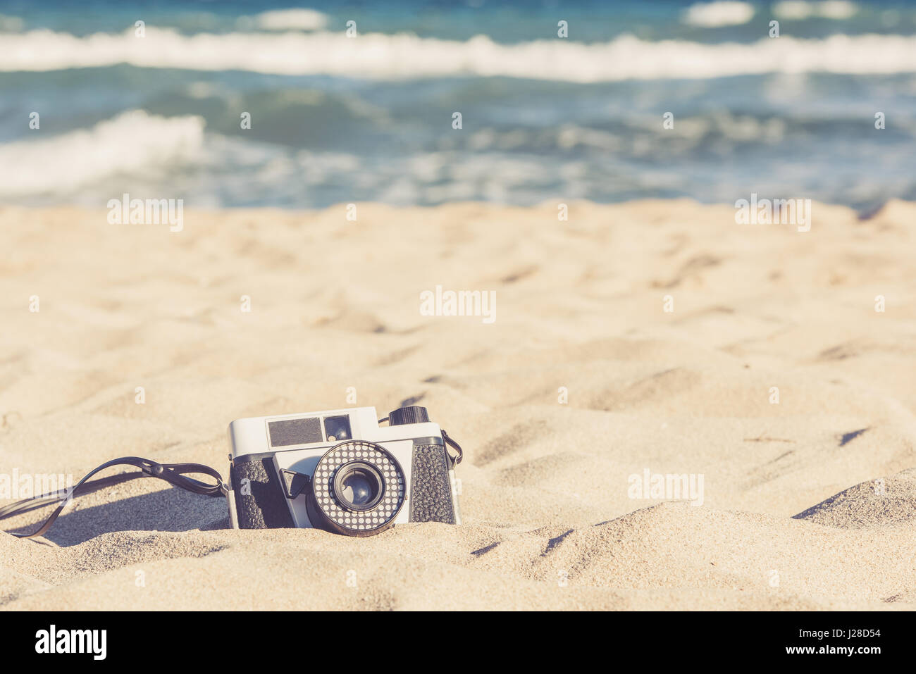 Vecchia fotocamera vintage giacente nella sabbia sulla spiaggia Foto Stock