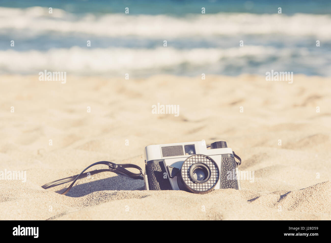 Vecchia fotocamera vintage giacente nella sabbia sulla spiaggia Foto Stock