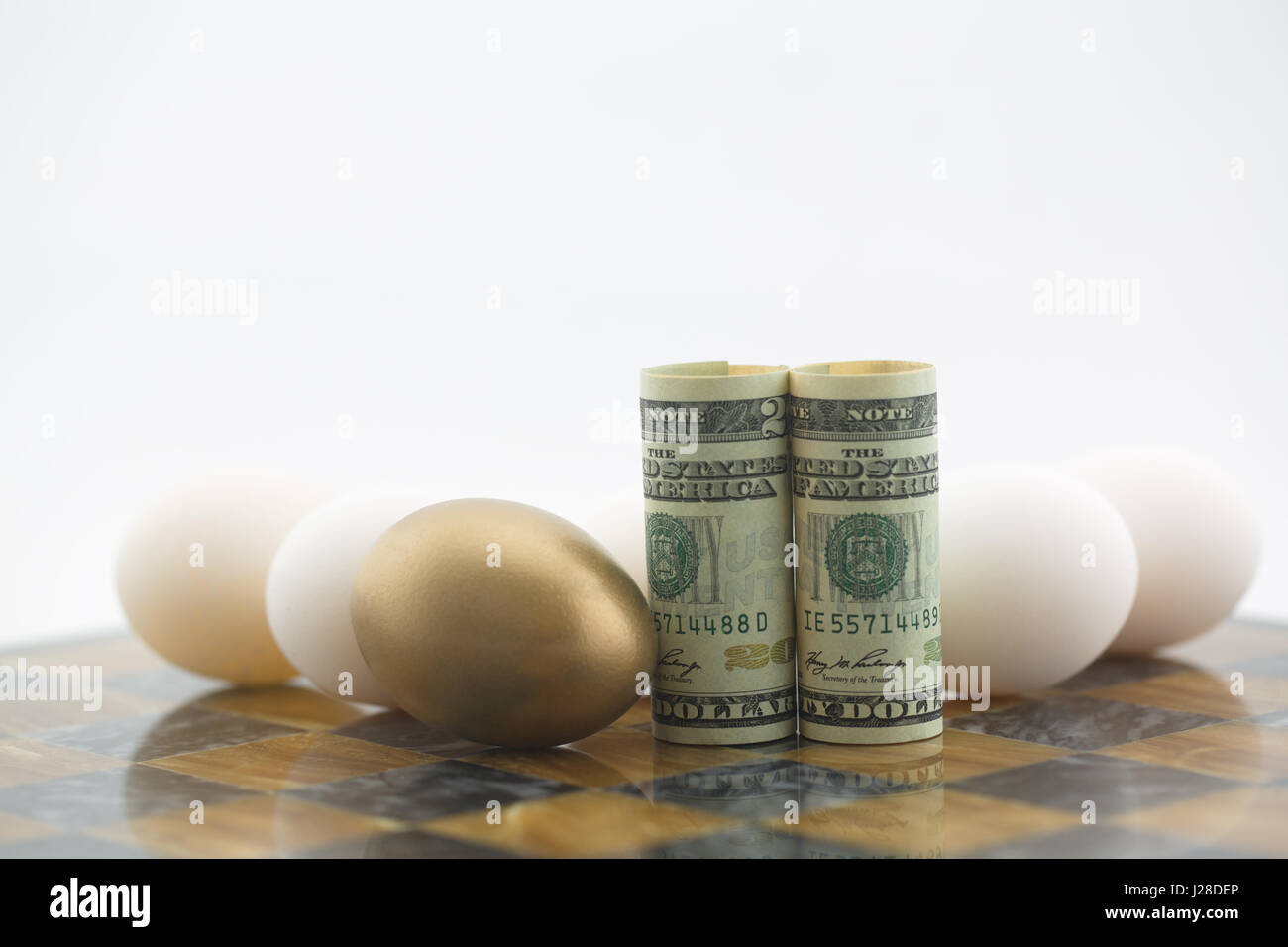 Nido d'oro uovo spicca tra le molte uova deposte sul bordo del gioco con la moneta americana. Concettuale immagine finanziario riflette la leadership vincente e inve Foto Stock