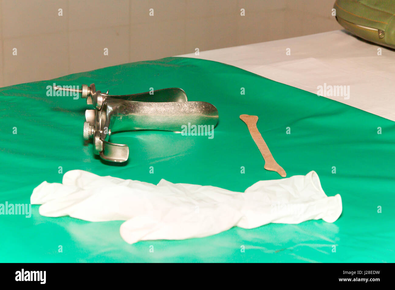 Colposcop, spatola e guanti medici su una pulita coperta di verde (attrezzature speculum vaginale) per (Pap test) ginecologia ispezionare esame ca cervicale Foto Stock