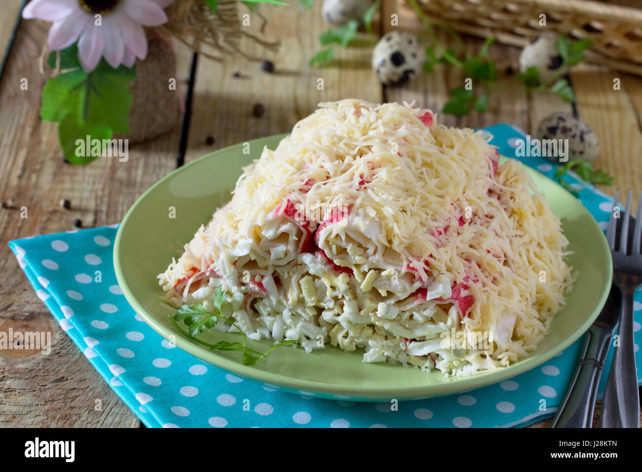 Insalata con bastoncini di granchio, uova, formaggio e aglio. Antipasto di festa su di un tavolo di legno. Foto Stock
