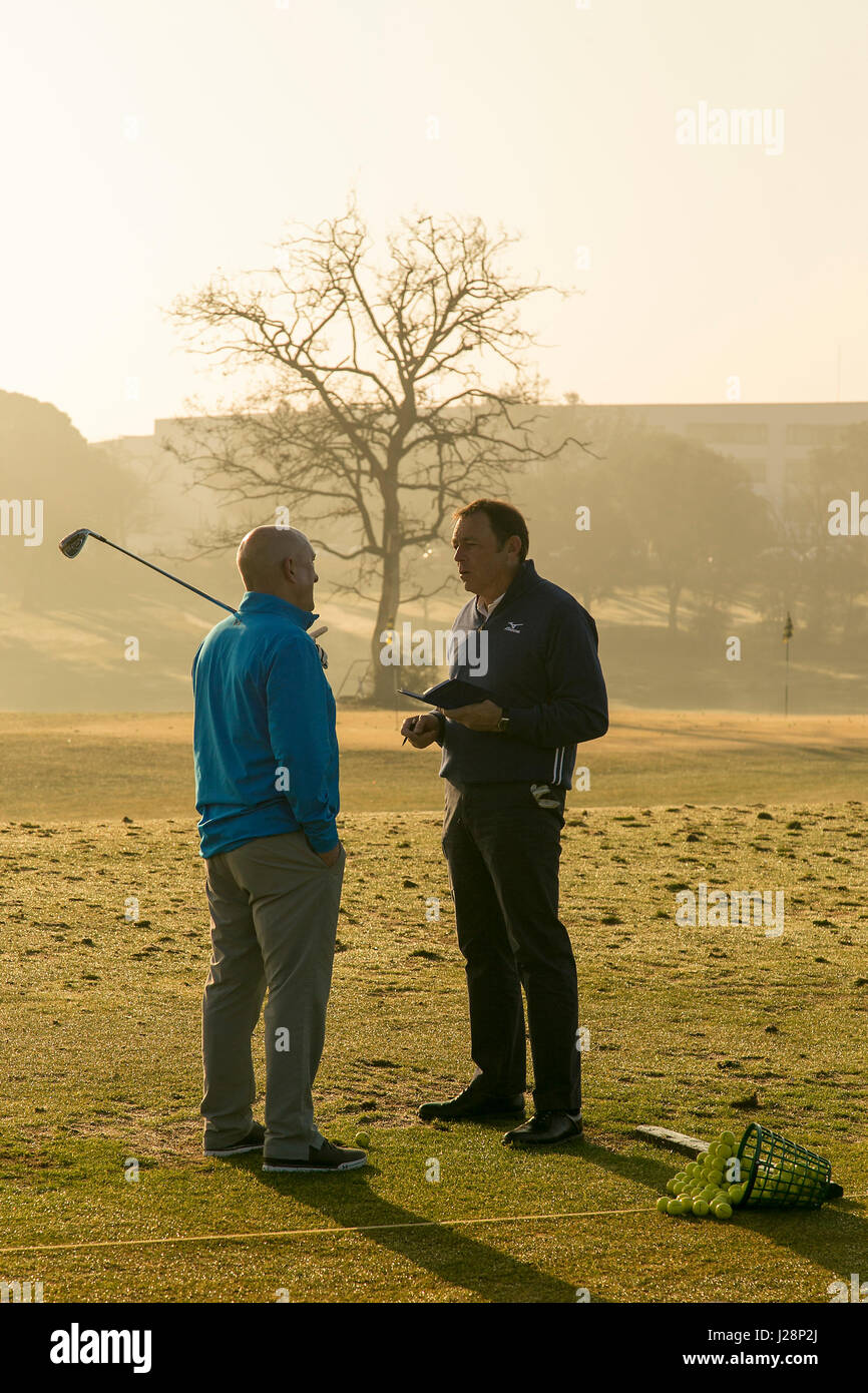 Gli amanti del golf swinging golf club in inizio di mattina di sole su una pratica gamma di guida all'alba. Foto Stock