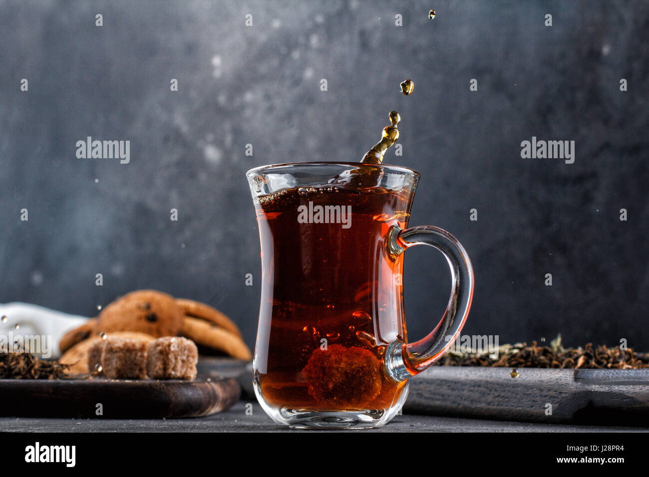 Un tappo di tè con spruzzi ancora in vita su uno sfondo nero Foto Stock