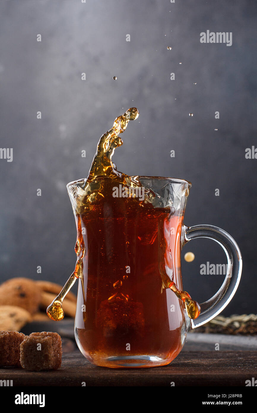Un tappo di tè con spruzzi ancora in vita su uno sfondo nero Foto Stock