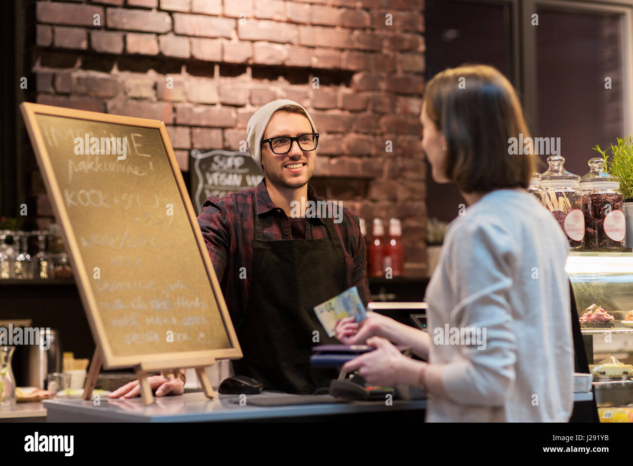 Felice il barman e la donna pagare denaro presso il cafe Foto Stock