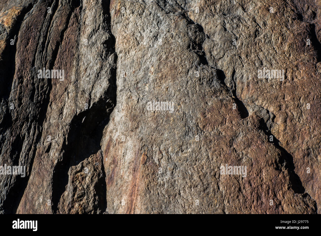 Dettaglio della roccia di granito con tracce di ferro rosso in superficie e spiovente con segni di erosione Foto Stock
