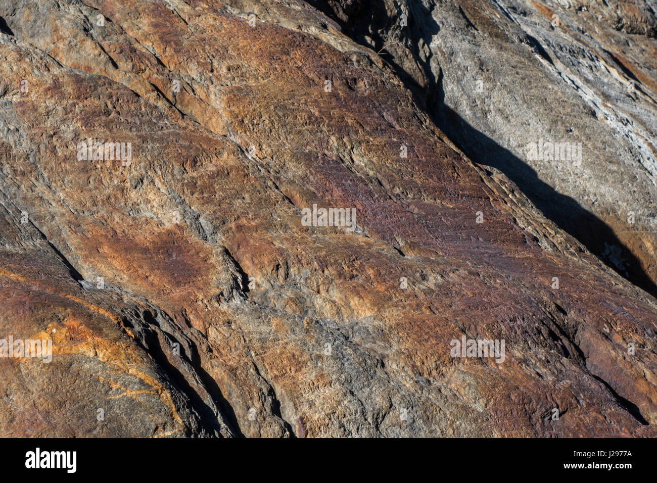 Dettaglio della roccia di granito con tracce di ferro rosso in superficie e spiovente con segni di erosione Foto Stock