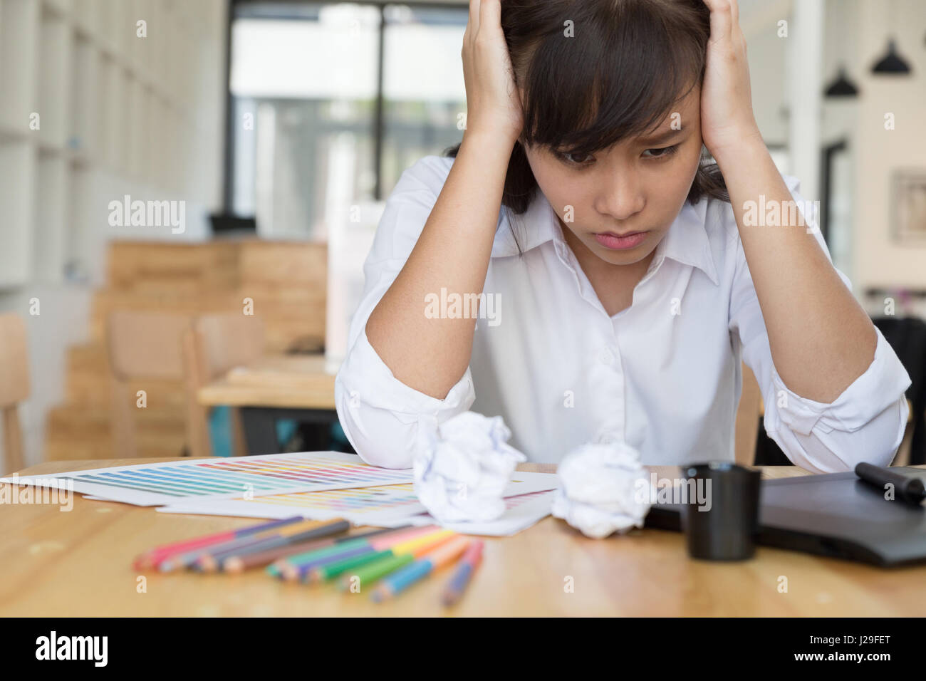 Designer grafica freelance sensazione di esaurimento, stressanti e ha mal di testa, stringendo la testa con le mani in ufficio con tavoletta digitale e il campione di colore cata Foto Stock