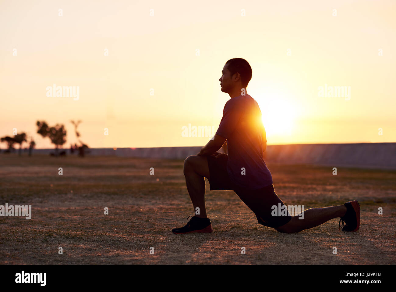 Athletic uomo asiatico stretching le sue gambe prima di una corsa mattutina Foto Stock