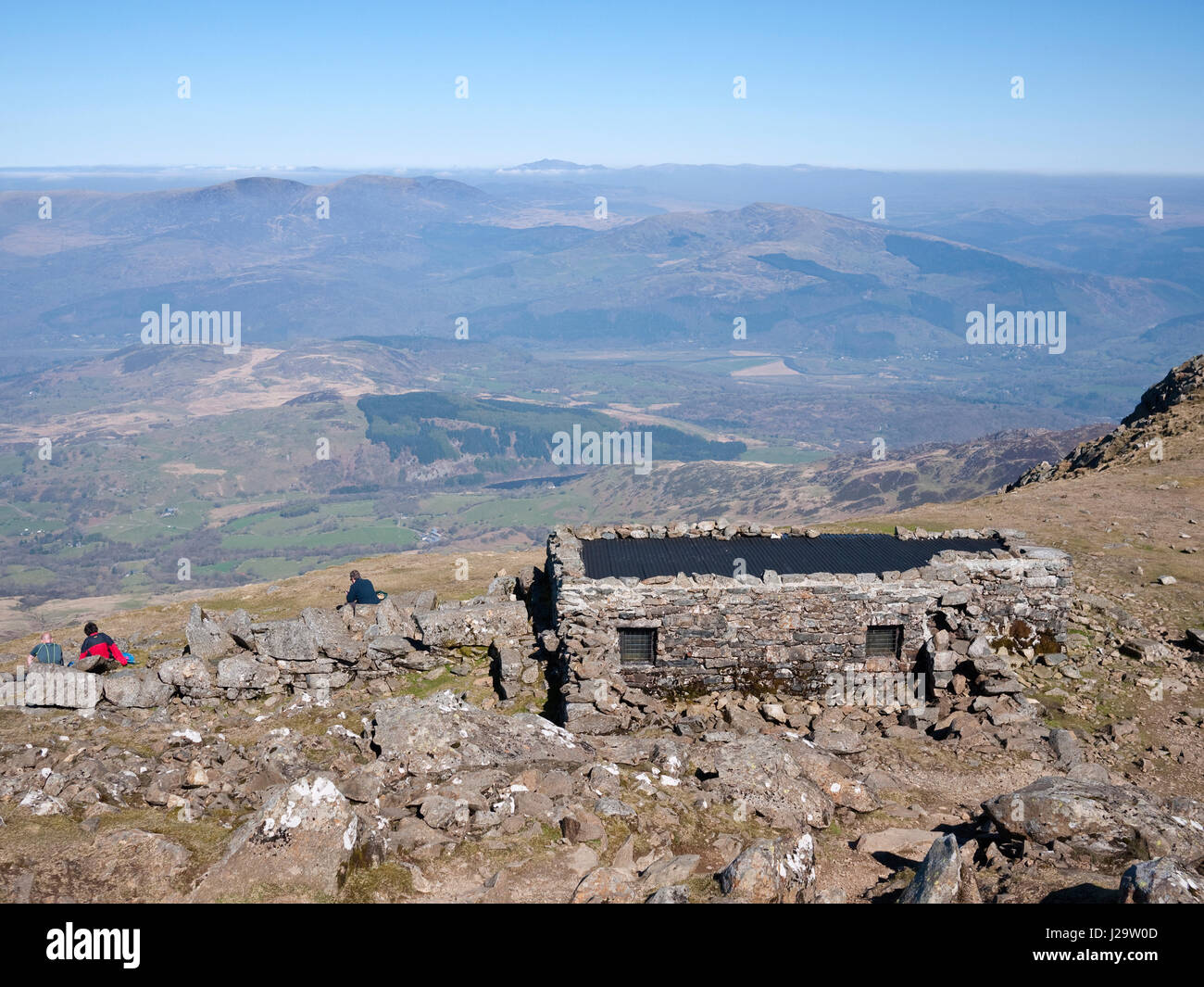 Gli escursionisti al di fuori del riparo del vertice su Cadair Idris. La vista è a nord, sopra le montagne Rhinog ad un distante Snowdon Foto Stock