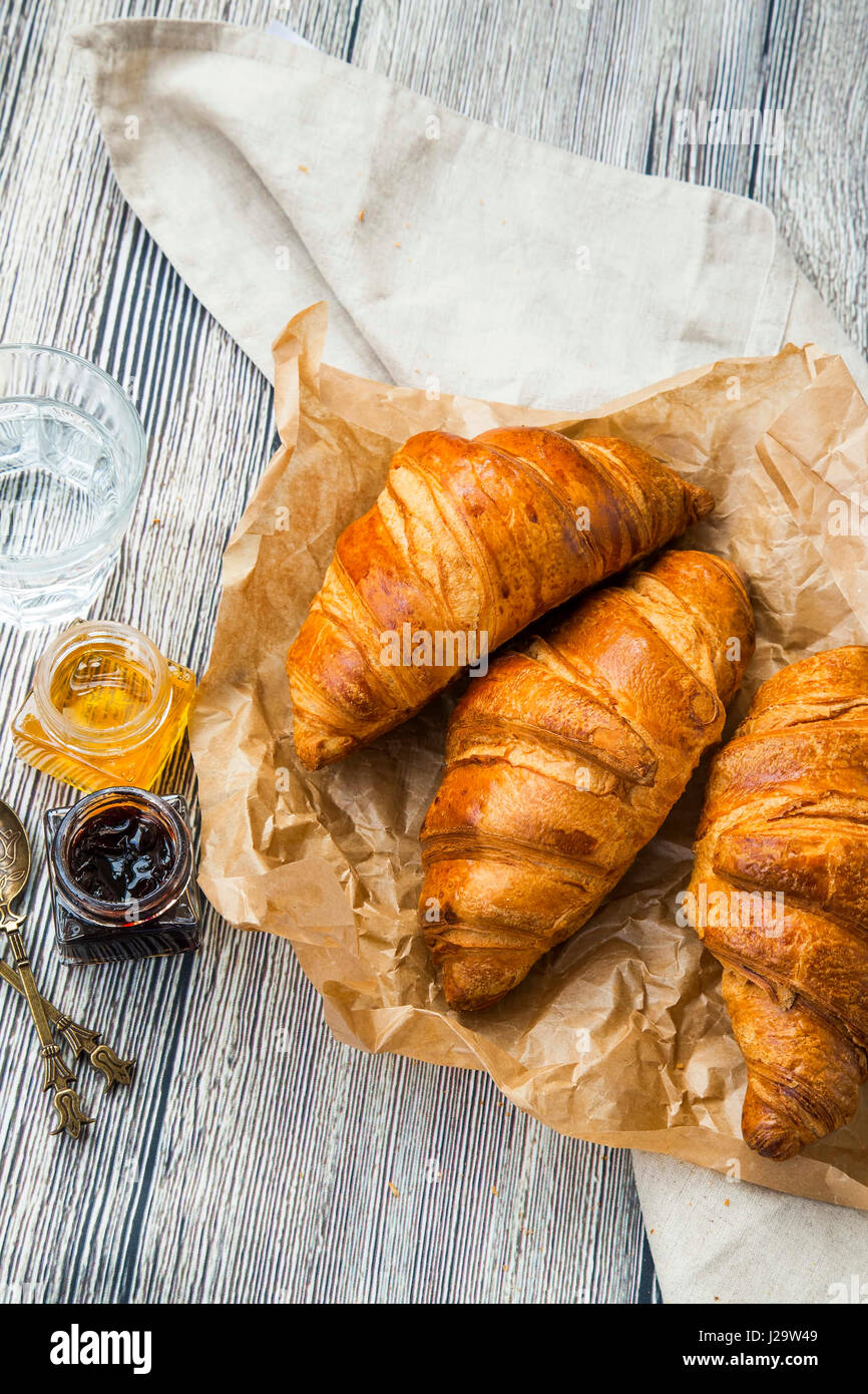 Croissant Pasticceria francese, burrosa pasta con prosciutto vasi su sfondo di legno Foto Stock