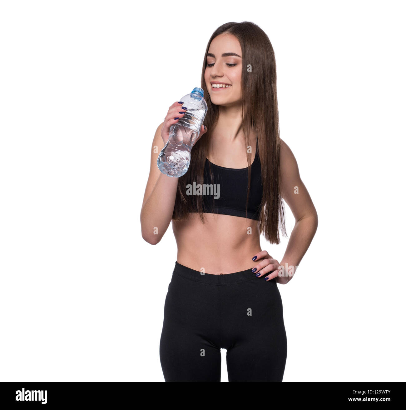 Femmina positivo modello fitness dopo allenamento tenendo un bottiglia di acqua pura su sfondo bianco Foto Stock