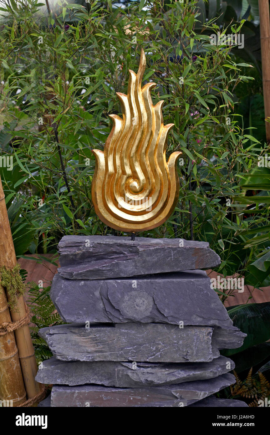 Una simbolica fiamma oro in un giardino Thai di serenità e di pace Foto Stock