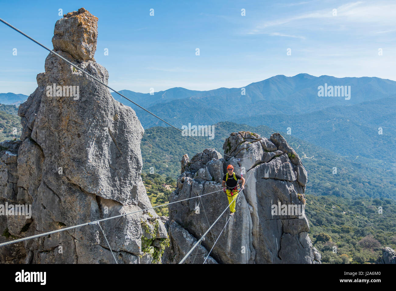 Scalatore maschio indossando indumenti speciali e camminare sulla corda con il paesaggio sullo sfondo Foto Stock