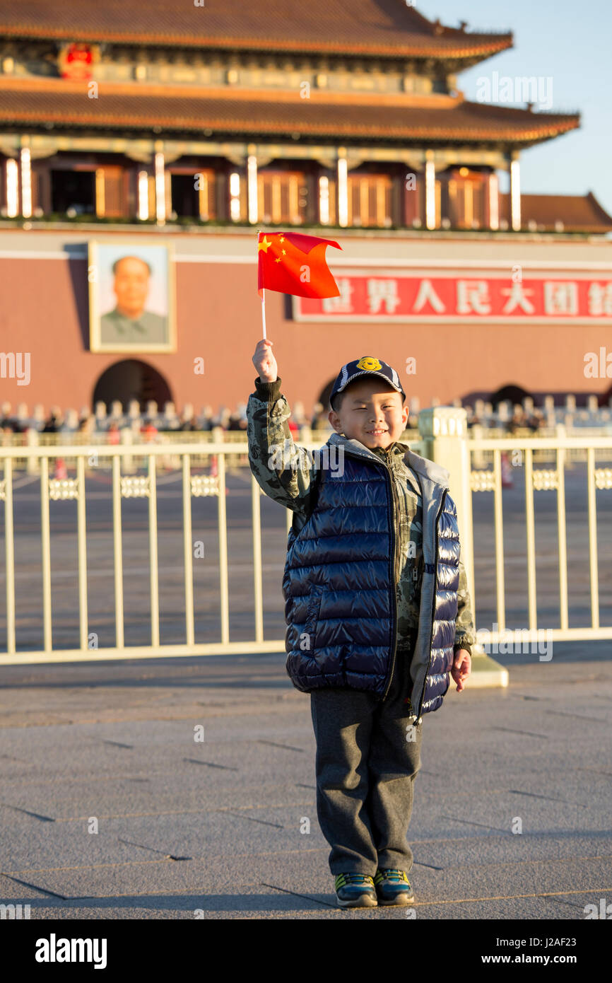 Cina, Pechino, ragazzo giovane trattiene piccola bandiera cinese mentre posa per istantanee dopo il cerimoniale di bandiera alzata in piazza Tiananmen sulla mattina autunnale Foto Stock