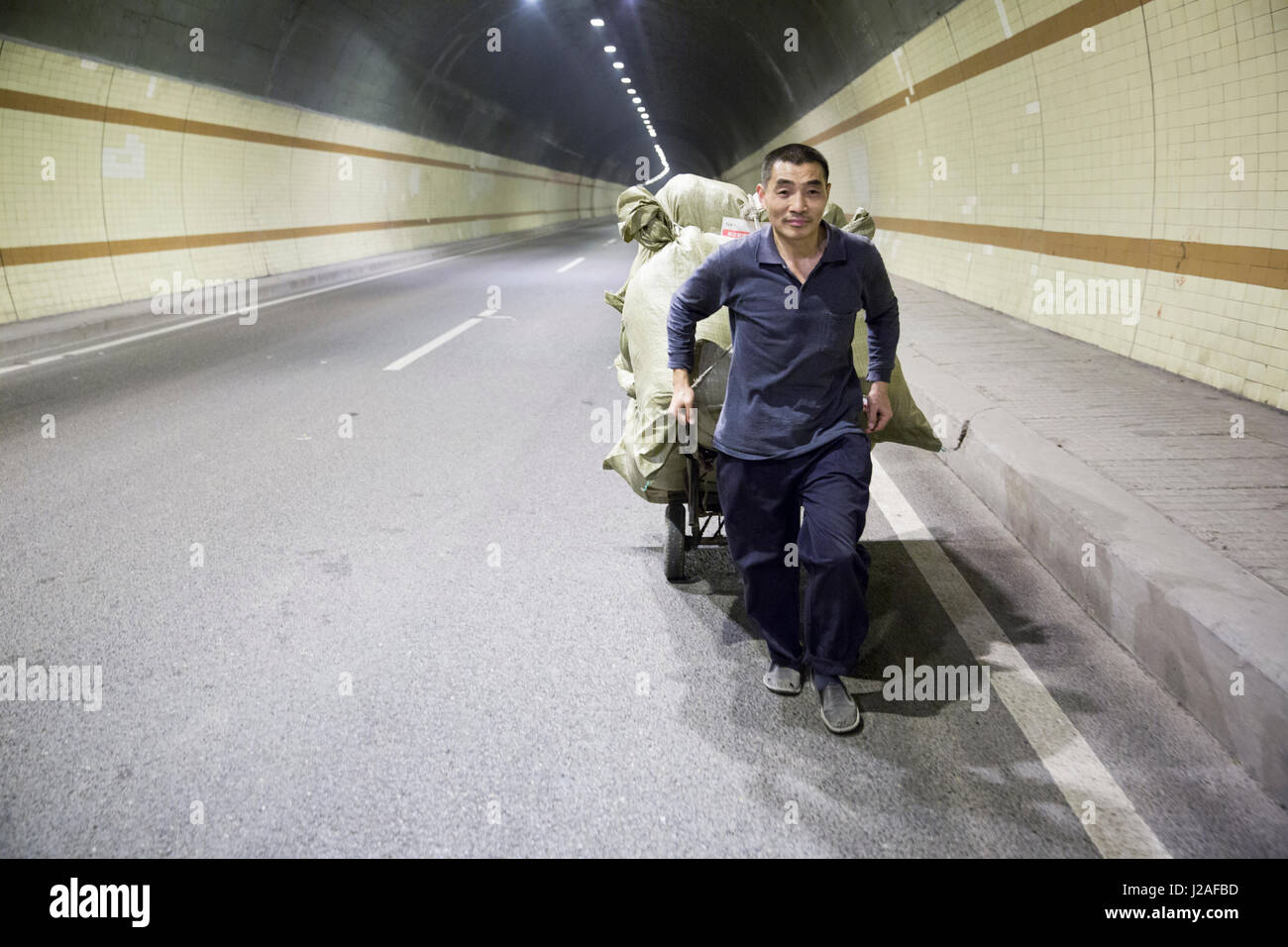 Cina, Chongqing, operaio cale massiccio carico portato dal carrello dalle rive del fiume Yangtze attraverso tunnel occupato attraverso la città Foto Stock