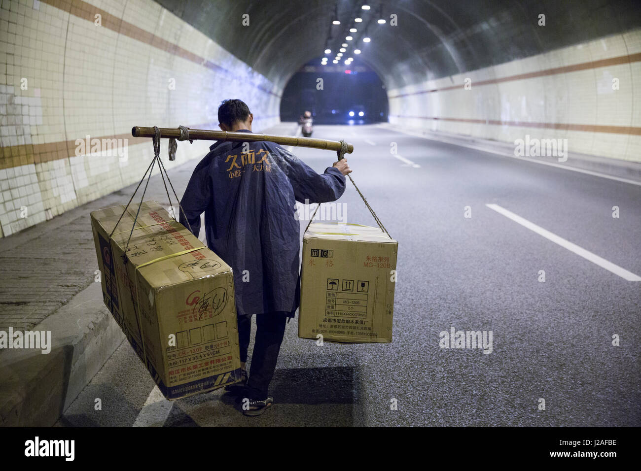 Cina, Chongqing, operaio cale massiccio carico trasportato sul palo di bambù dalle rive del fiume Yangtze attraverso tunnel occupato attraverso la città Foto Stock