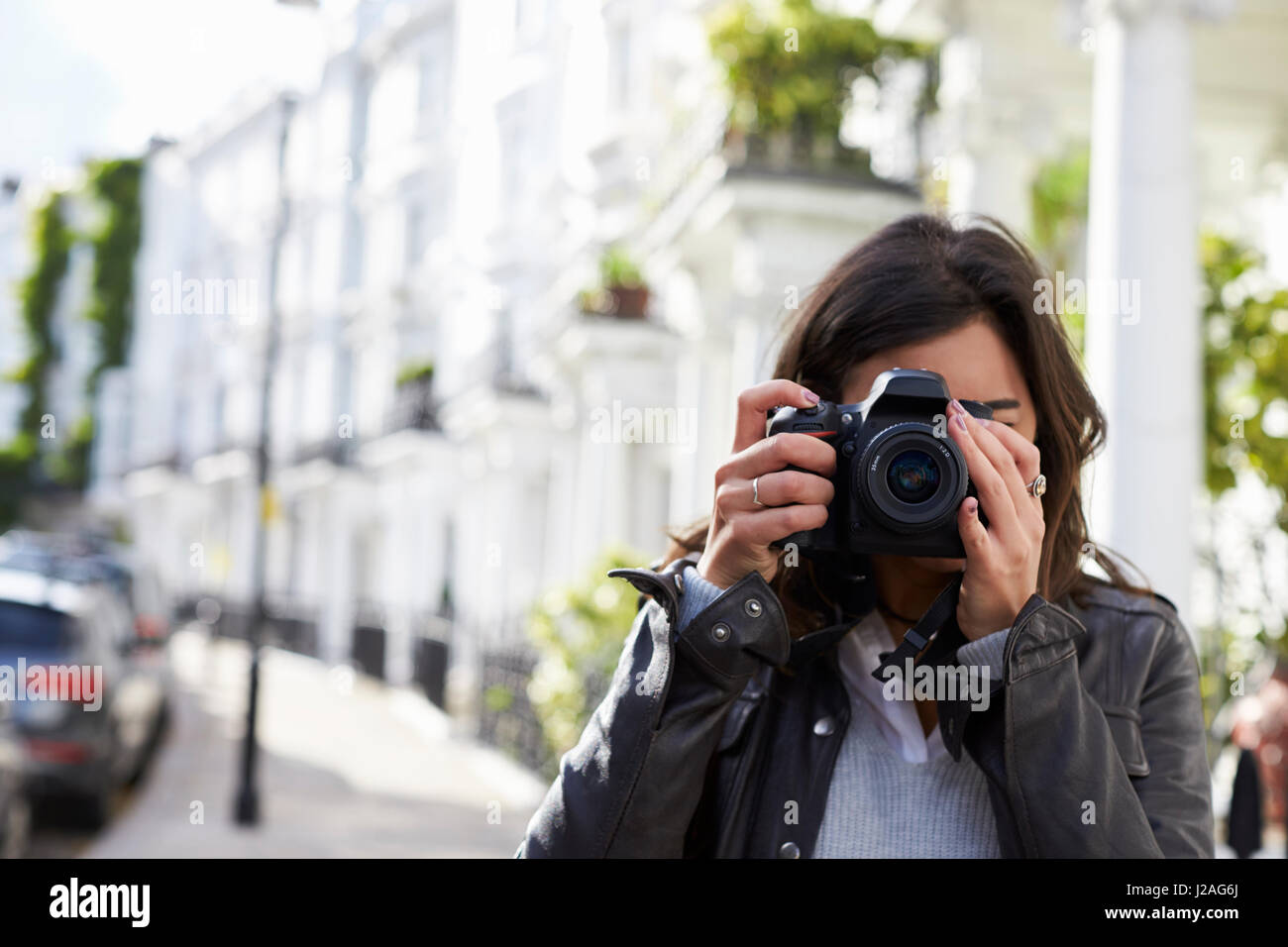 Giovane donna in strada prendendo foto con fotocamera reflex, close up Foto Stock