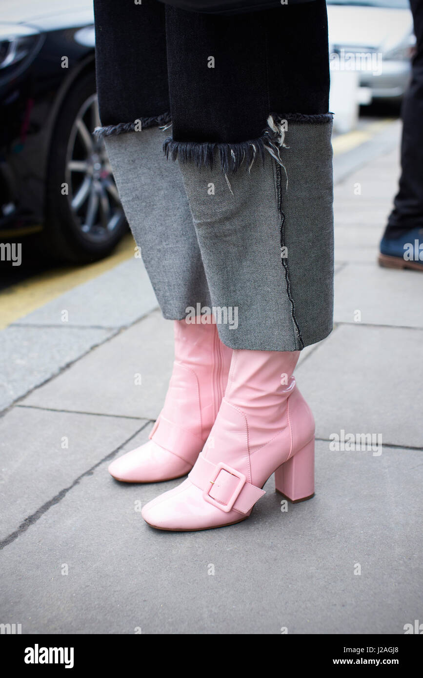 Londra - febbraio, 2017: sezione bassa di moda donna che indossa jeans con grande turn-ups e rosa stivali in pelle con cinturino e fibbia in piedi in strada durante la London Fashion Week, verticale, vista laterale Foto Stock