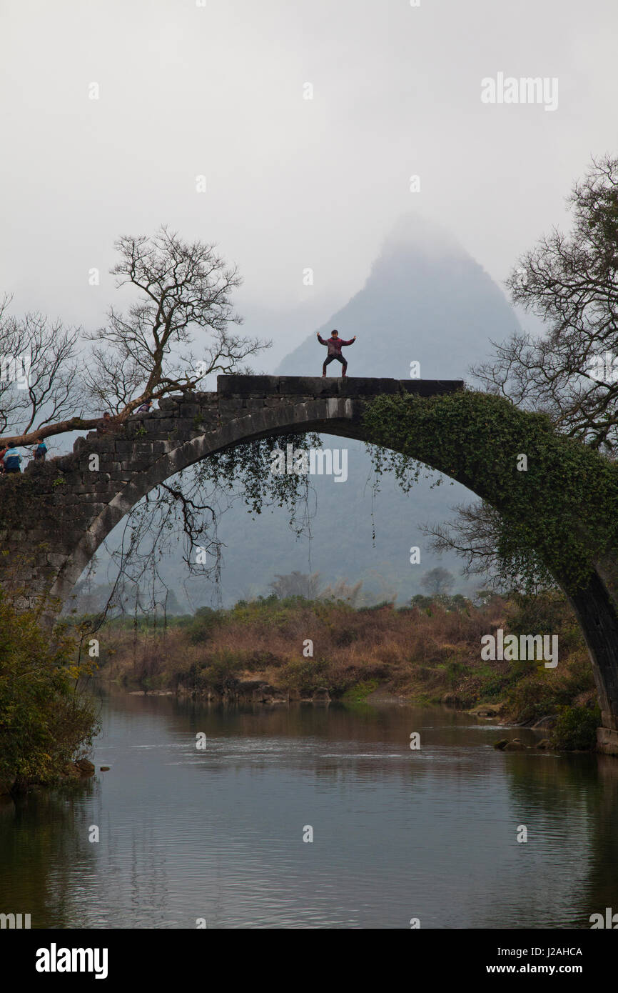 Cina, Yang Shou, giovane ragazzo sul ponte con le montagne del fiume Li Foto Stock