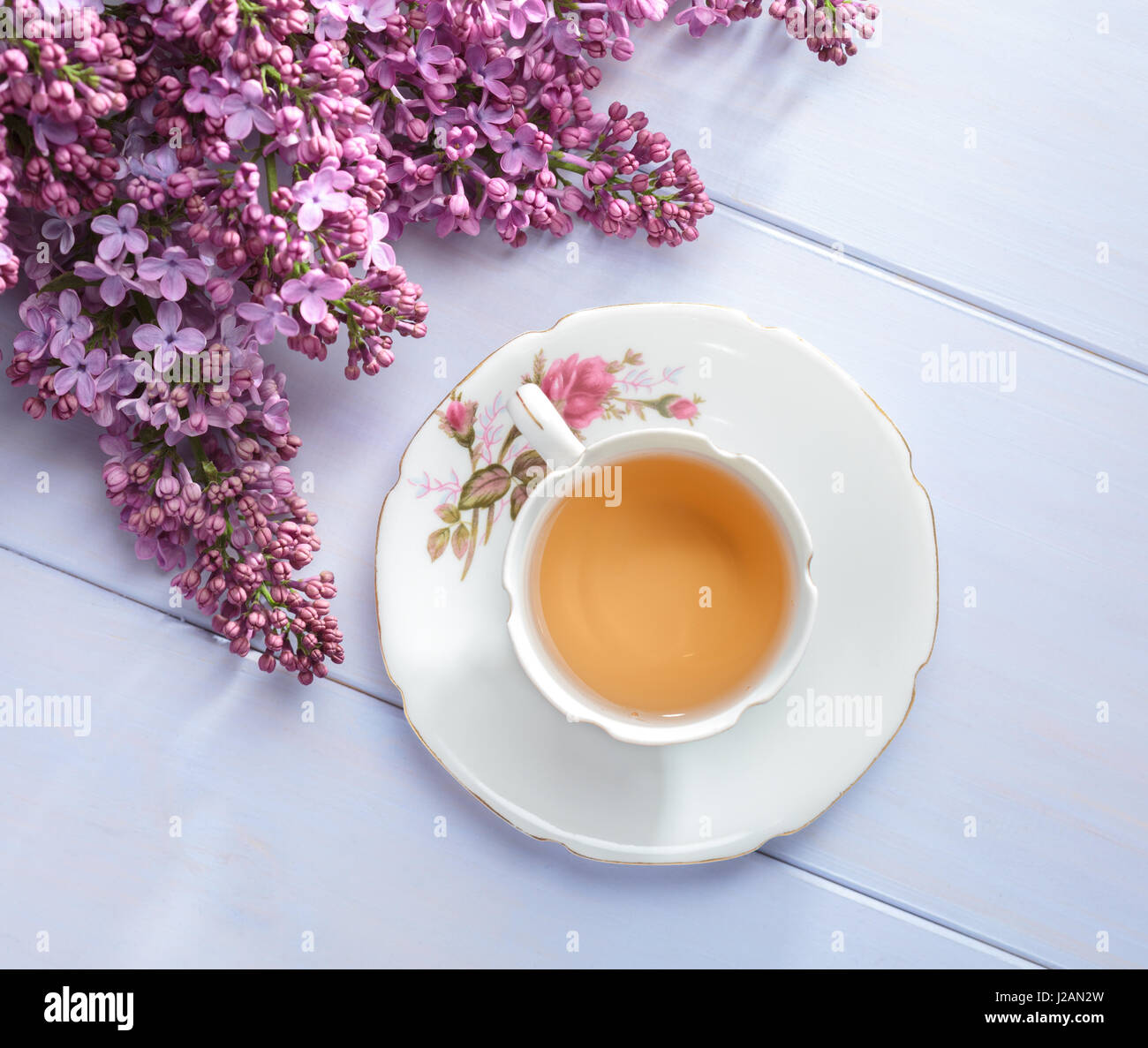 Tazza di tè e rami di fioritura lilla sul tavolo di legno. Foto Stock