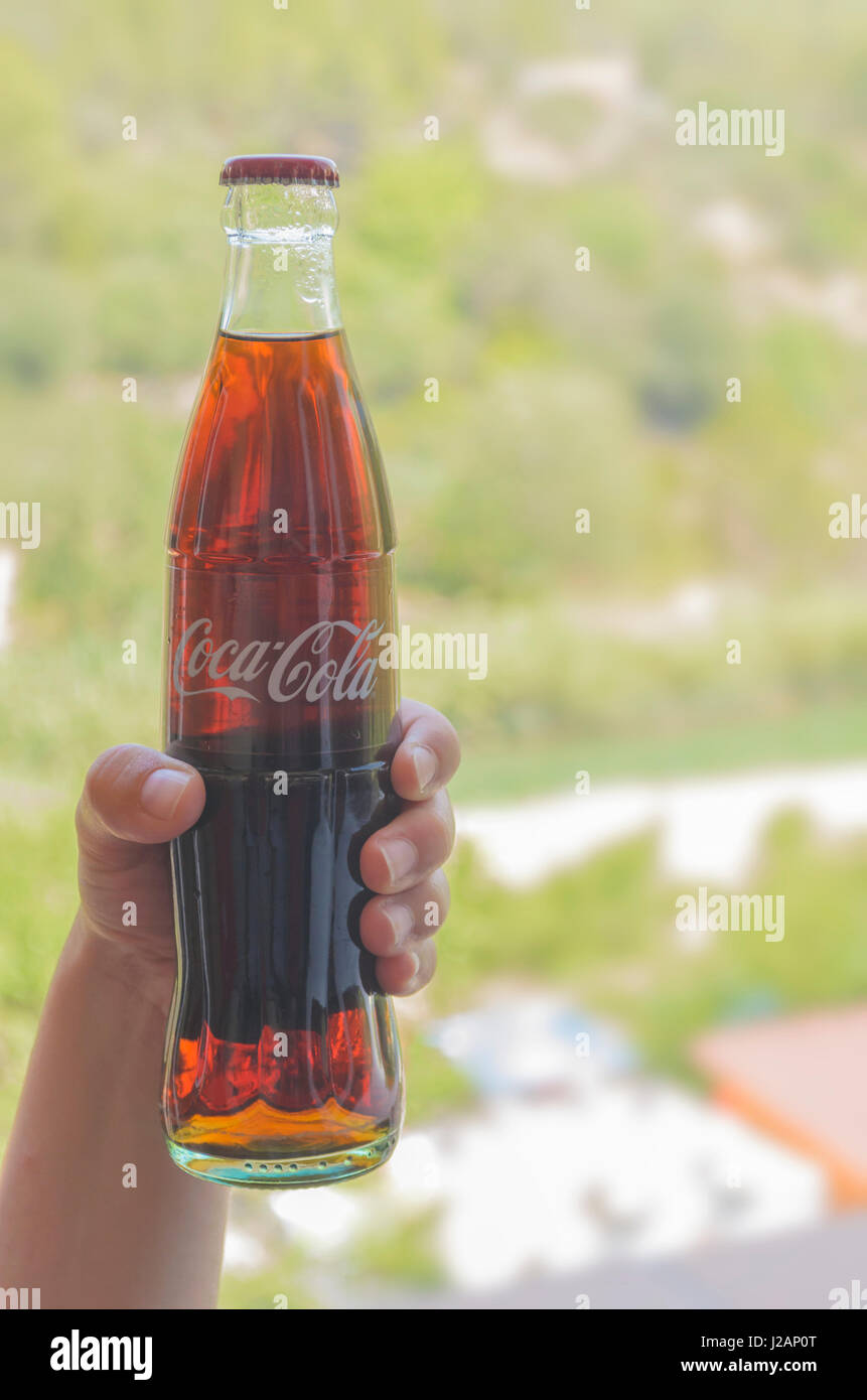 Mano con bottiglia di Coca Cola (330 mililiters - 33 cl) acquistato nel mese di agosto, 2016 in Spagna durante le vacanze estive. Soft il contrasto di colori e toni naturali Foto Stock