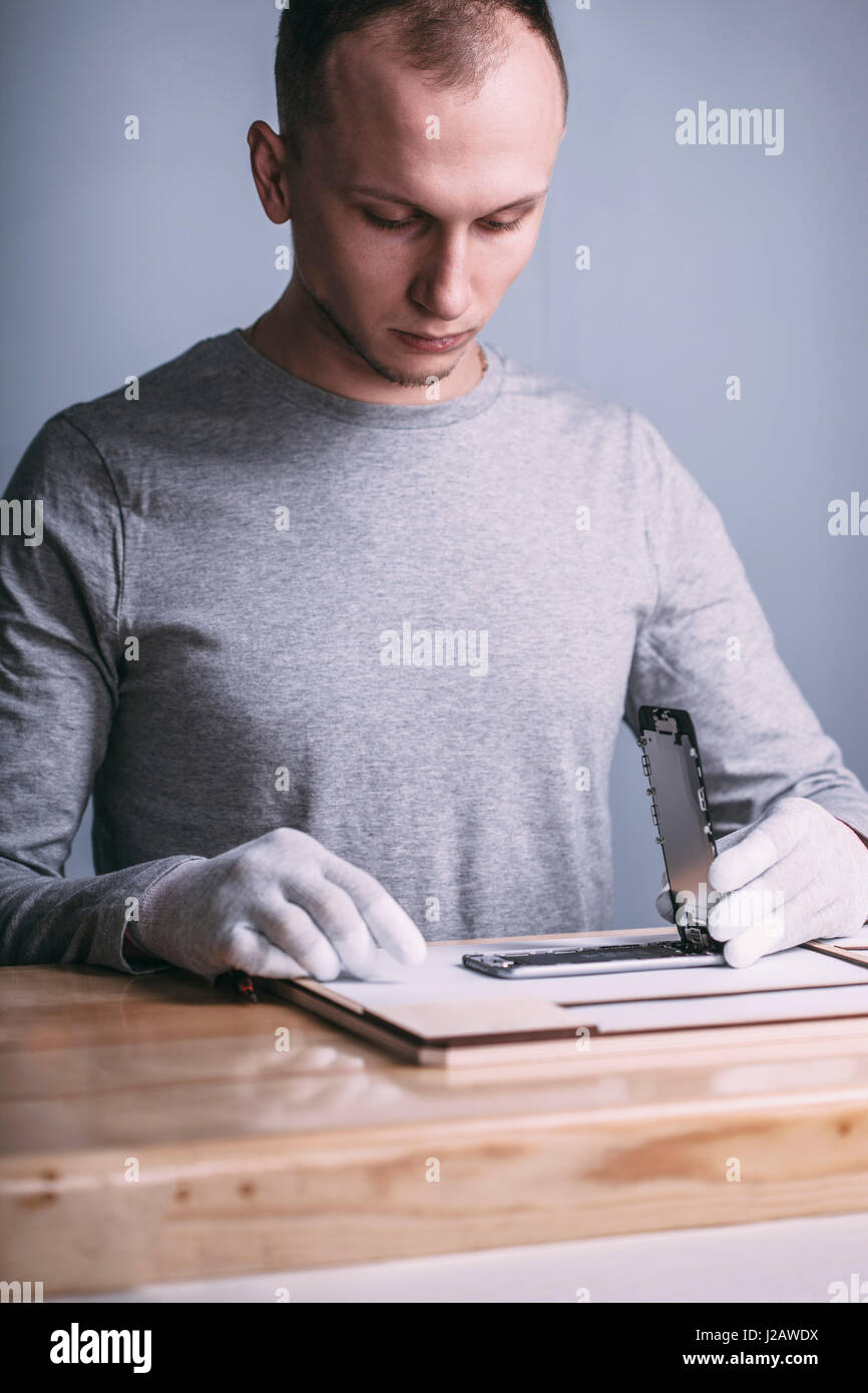 Giovane maschio il tecnico di riparazione cellulare al negozio di elettronica Foto Stock