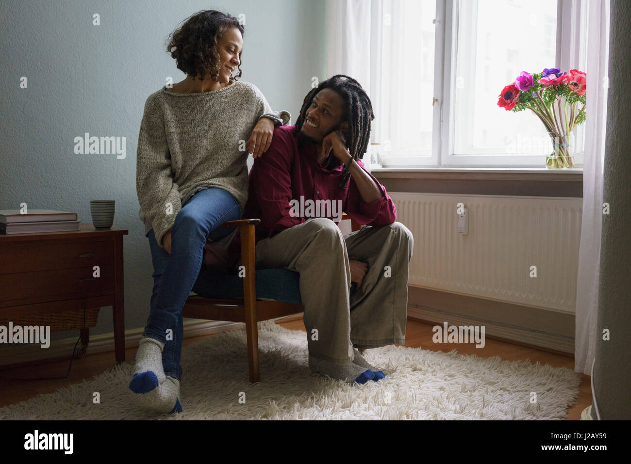 Coppia sorridente guardando ogni altro mentre è seduto sulla poltrona di casa Foto Stock