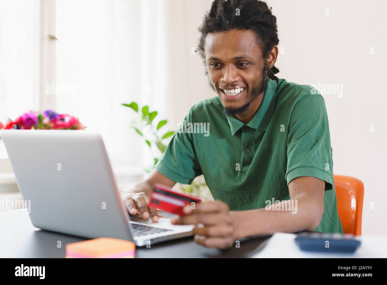 Uomo felice shopping online attraverso il portatile a casa Foto Stock