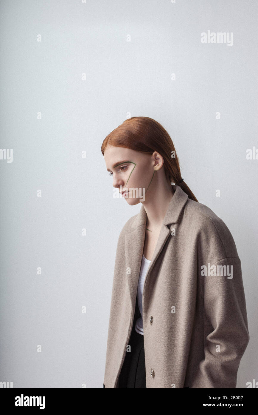 Premurosa ragazza adolescente in giacca con faccia vernice contro uno sfondo bianco Foto Stock