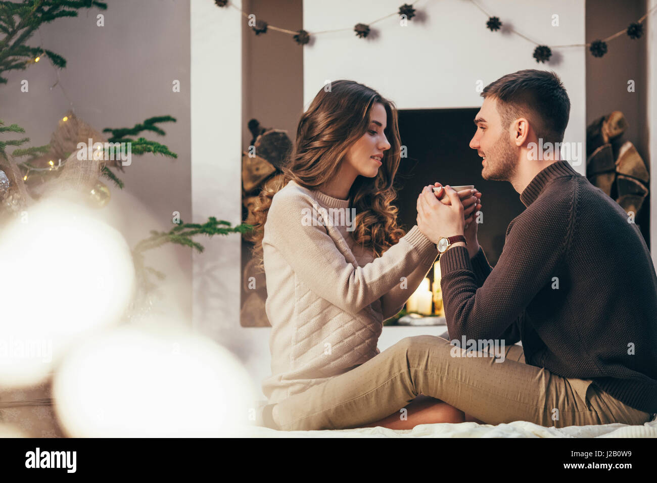 Coppia romantica avente il caffè seduti a casa durante il periodo di Natale Foto Stock
