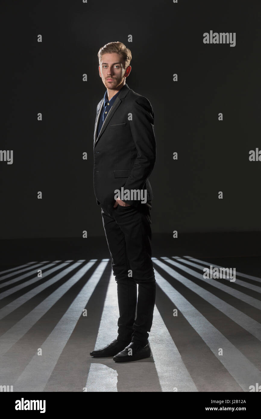 Ritratto di imprenditore formali da indossare in piedi su sfondo nero Foto Stock