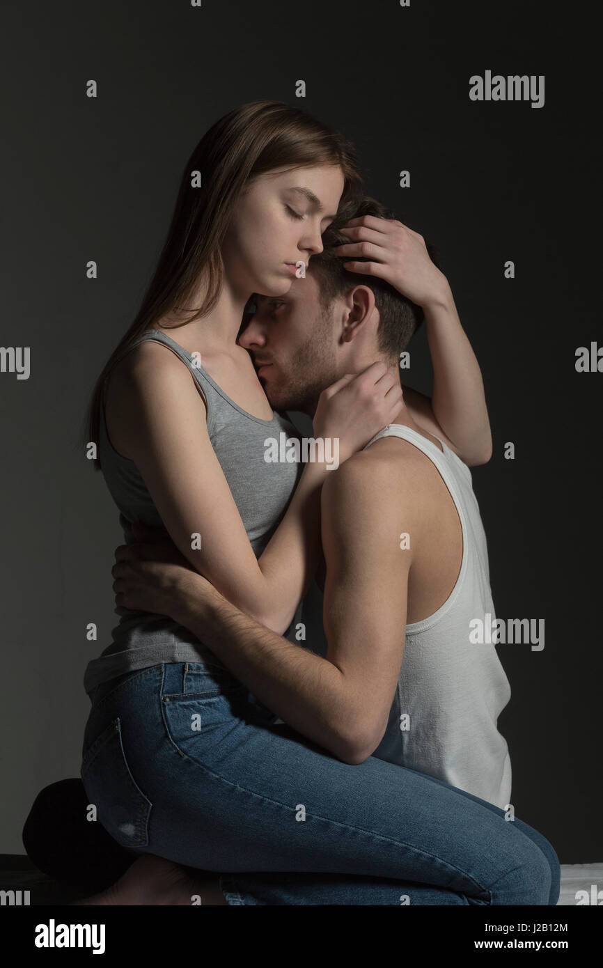 Romantico coppia giovane abbracciando contro uno sfondo grigio Foto Stock