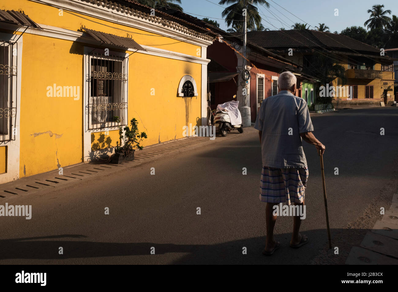 Un vecchio uomo cammina attraverso il vecchio quartiere portoghese di Fontainhas Foto Stock